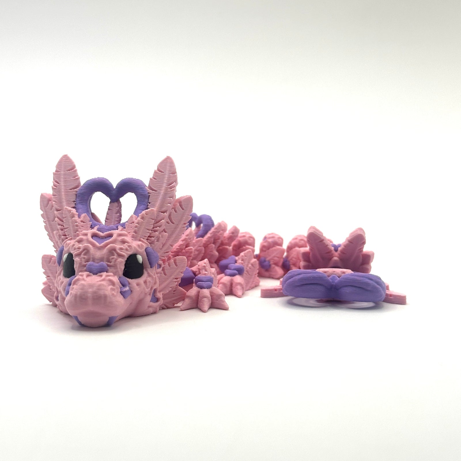 Pink dragon toy with purple accents on a white background