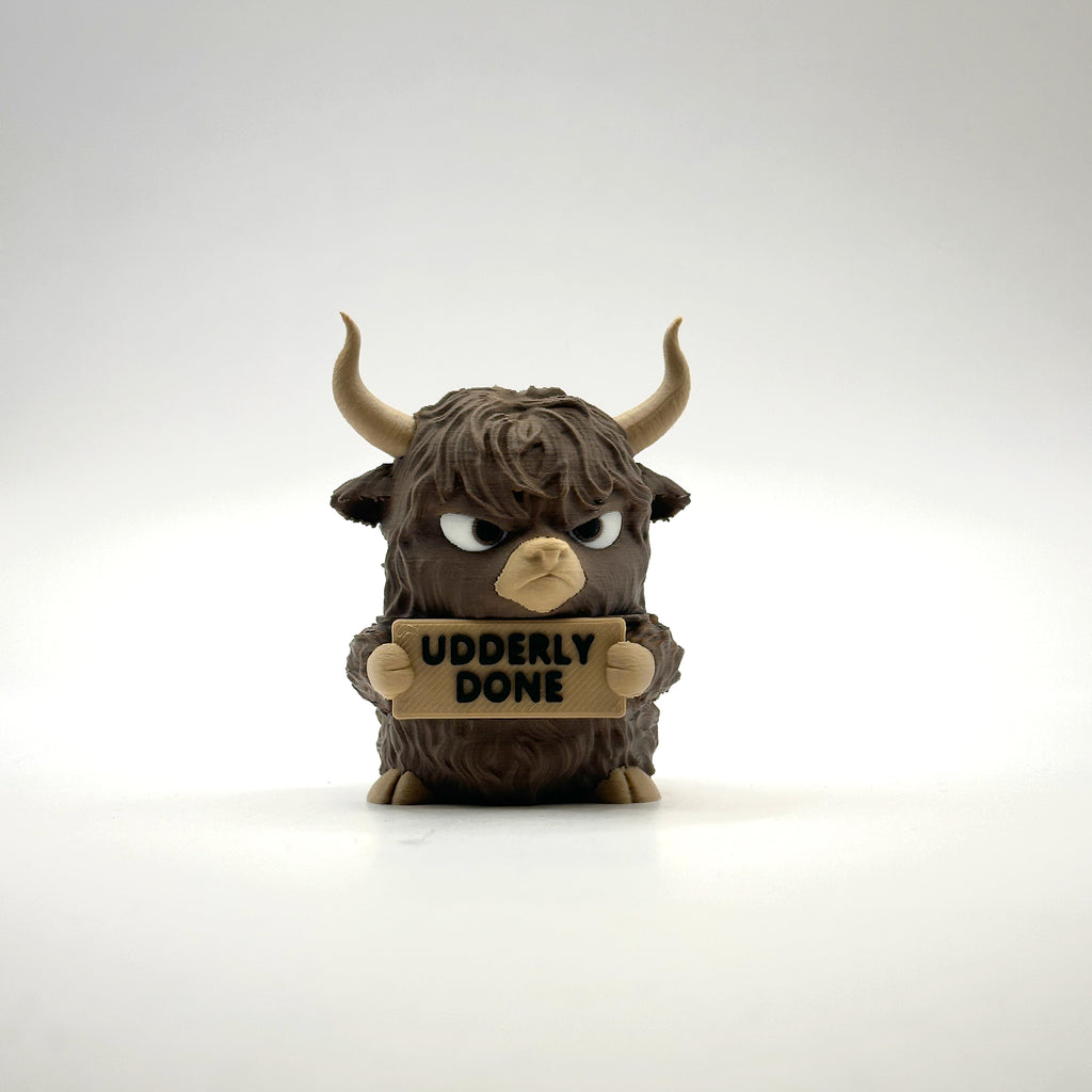 Udderly Done Highland Cow 3D printed desk buddy holding its sign, front view